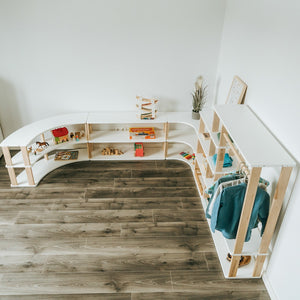 Overhead view of a children’s room arranged with curved Montessori shelves and modular wardrobe storage