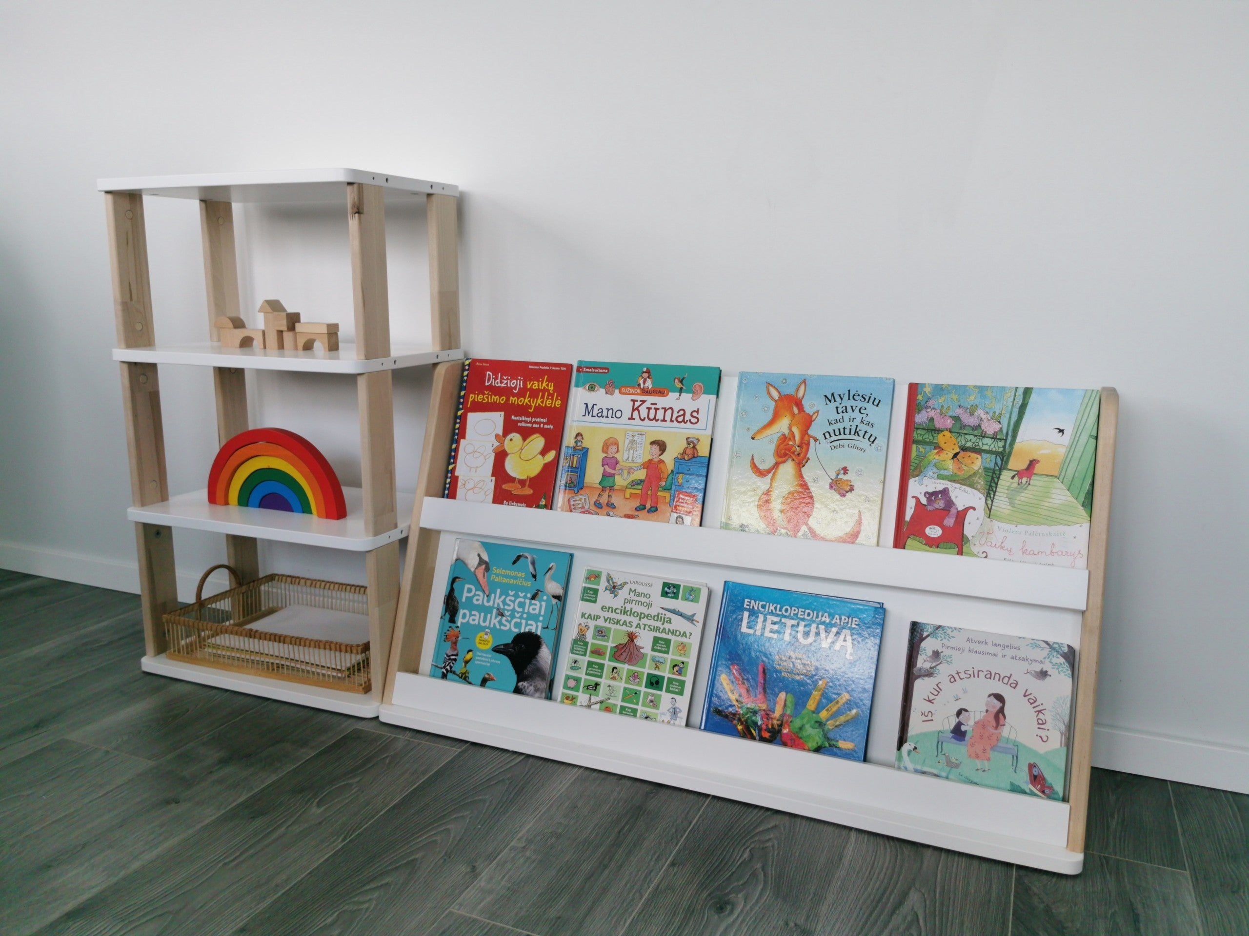 Modular Montessori bookshelf connected to a tall open shelf with books, wooden toys and rainbow decoration
