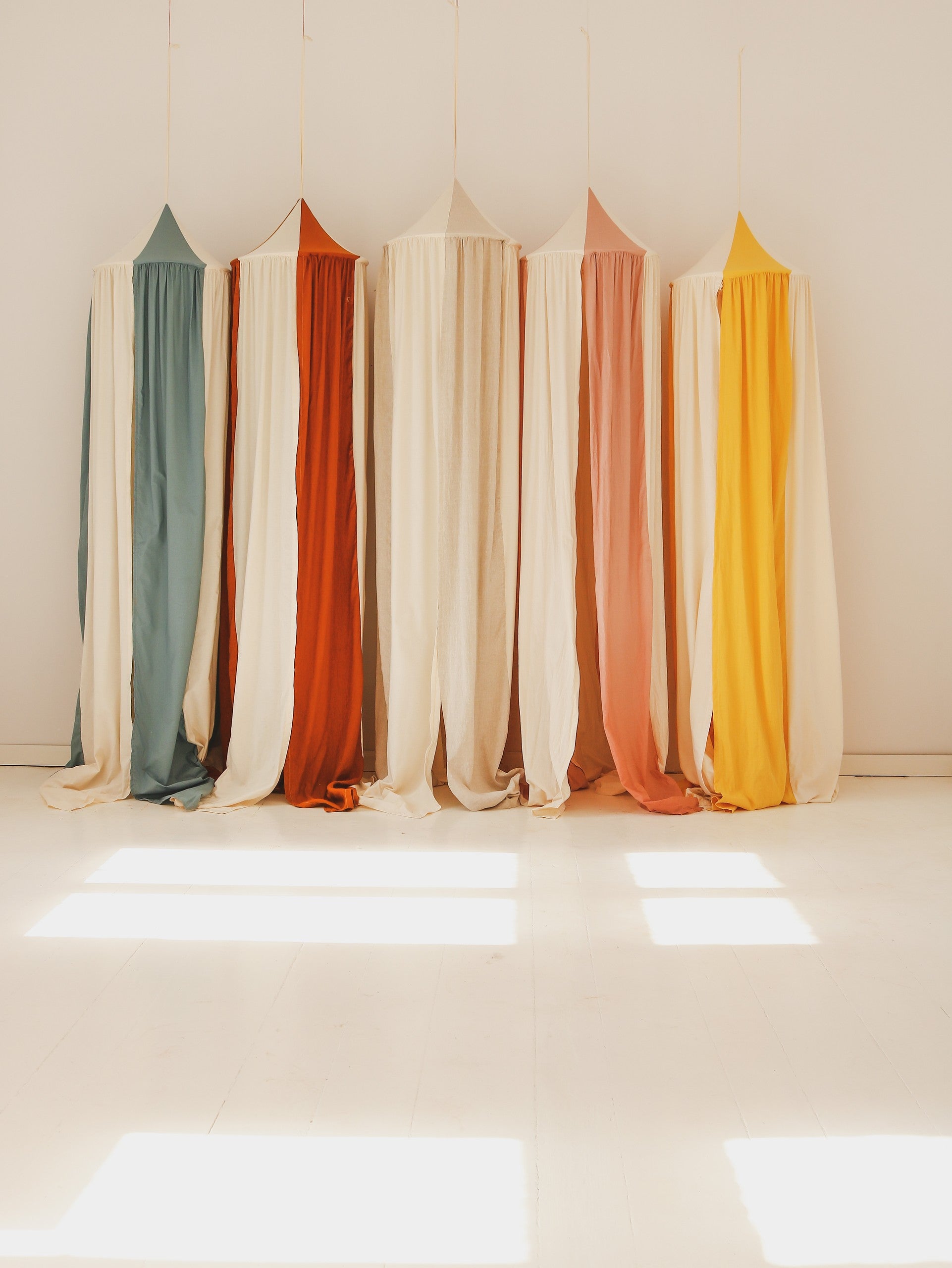 Five Moi Mili children’s canopies hanging together in a bright sunlit studio
