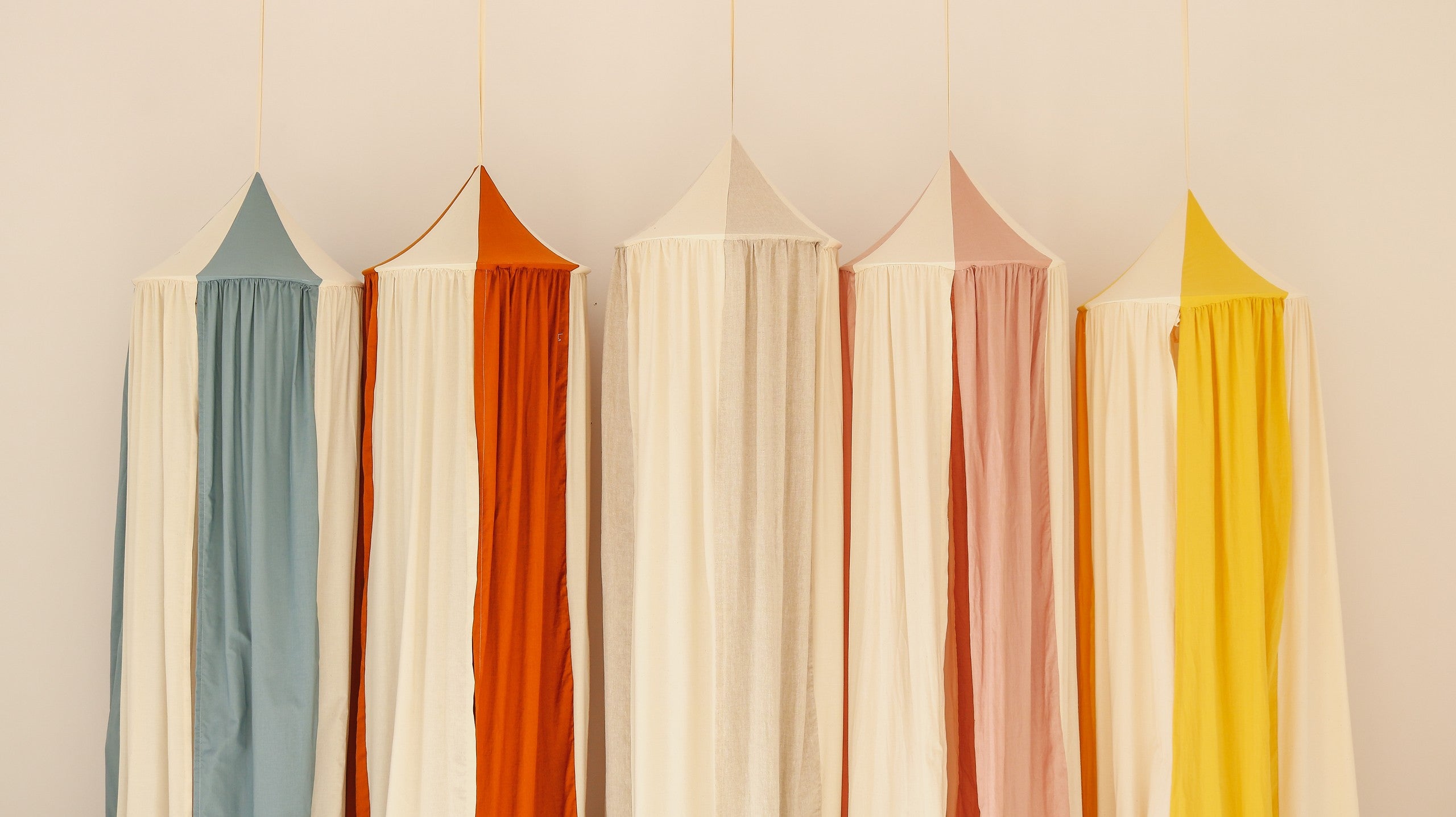 Blue Circus canopy displayed beside orange, cream, pink and yellow Moi Mili canopy colourways