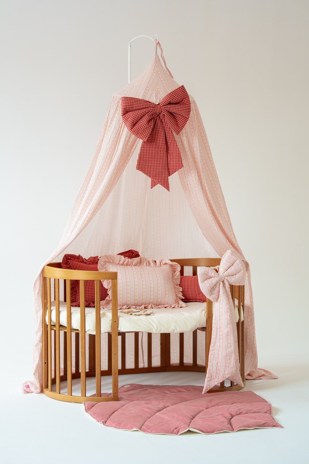 Moi Mili Vintage canopy styled above a round wooden child’s bed with a large burgundy bow and pink leaf play mat