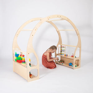 Child playing with toys inside wooden Montessori Play Stand and accessible toy shelves