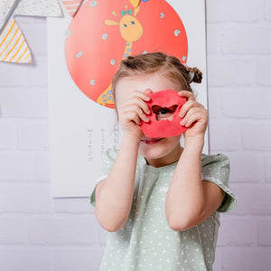 Child holding a red Easy Clay shape over one eye during creative modelling play