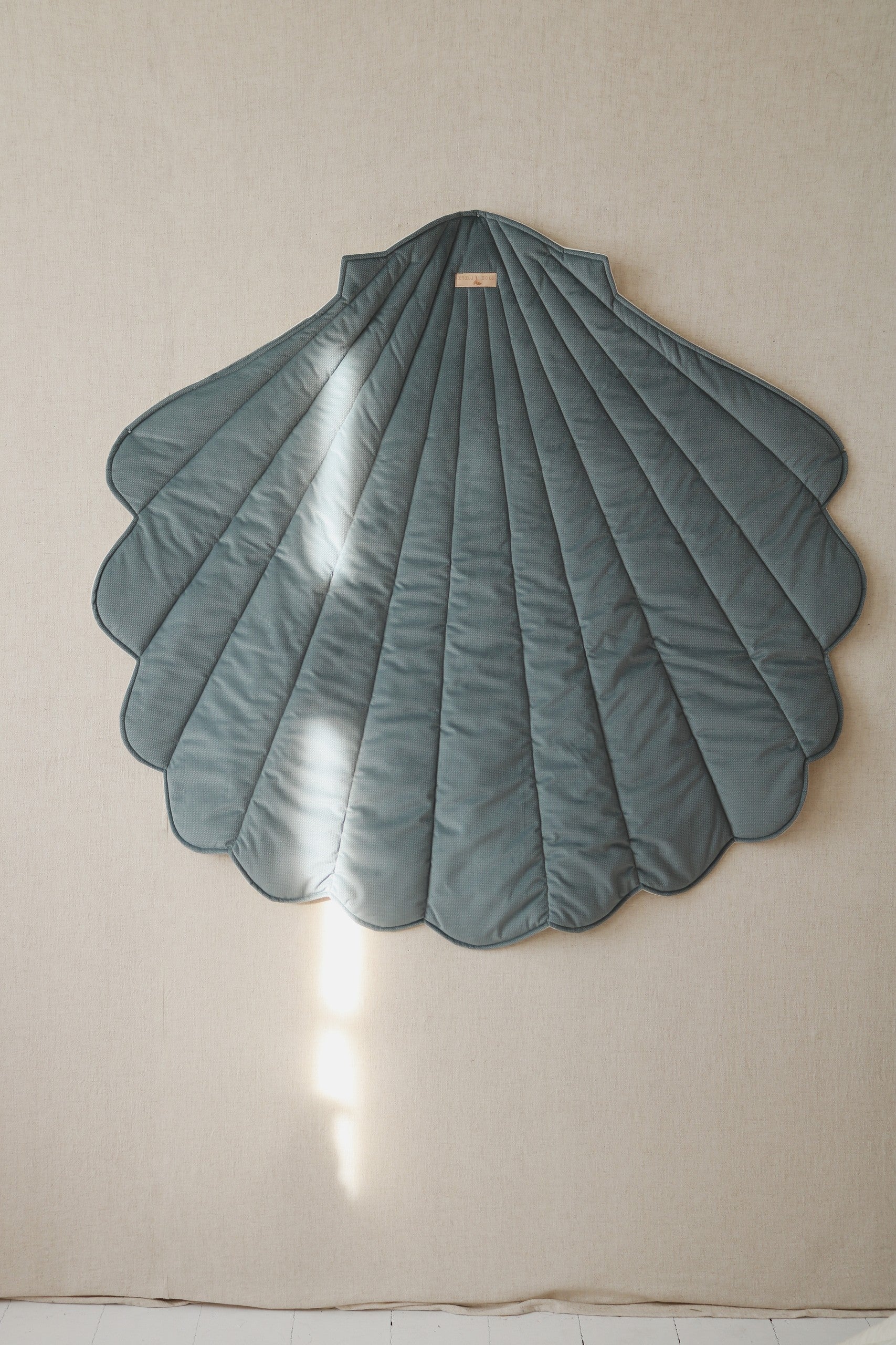 Blue-grey shell-shaped Moi Mili playmat displayed vertically as children’s room wall décor