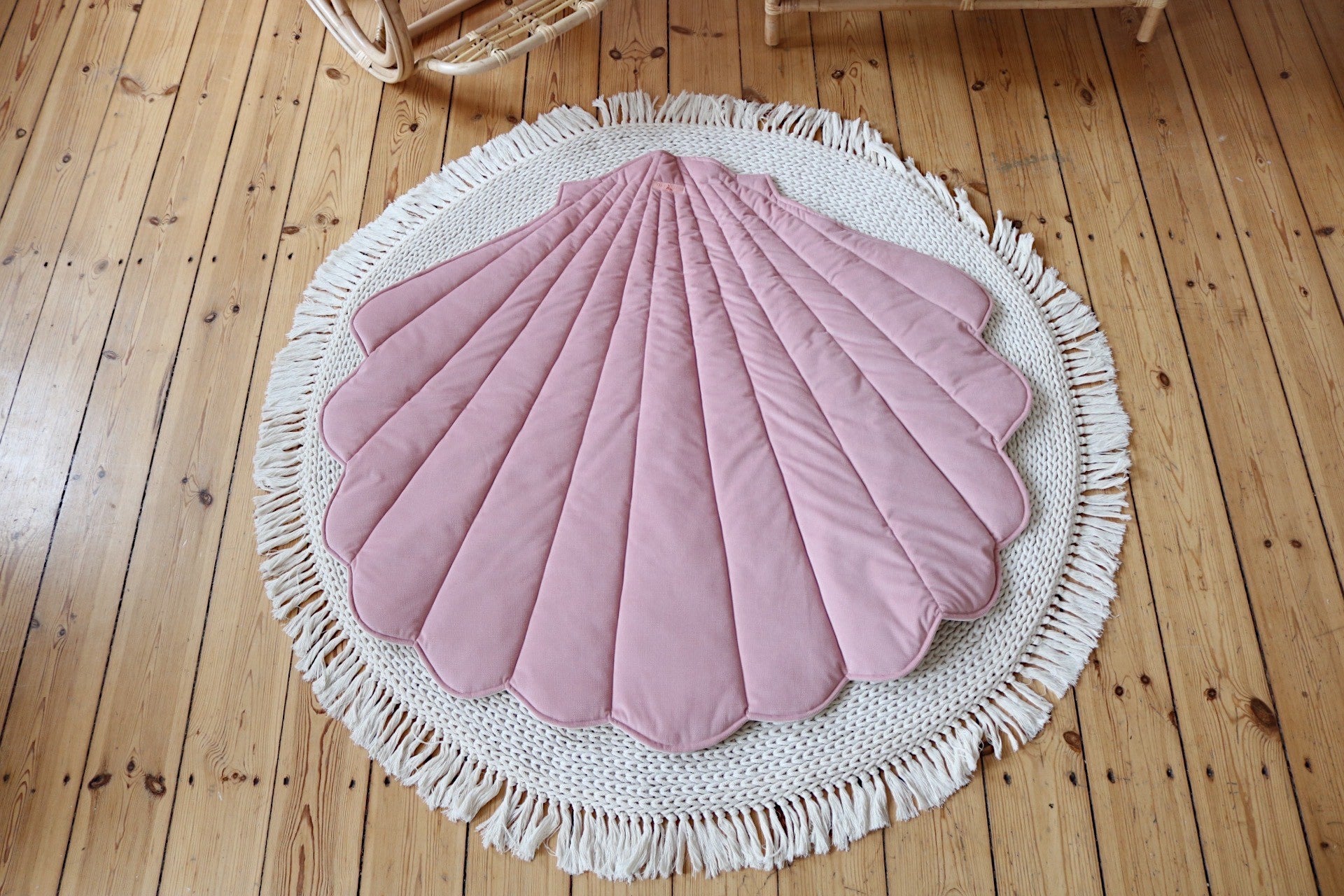 Powder pink Moi Mili shell playmat displayed on a round cream rug over natural wooden flooring