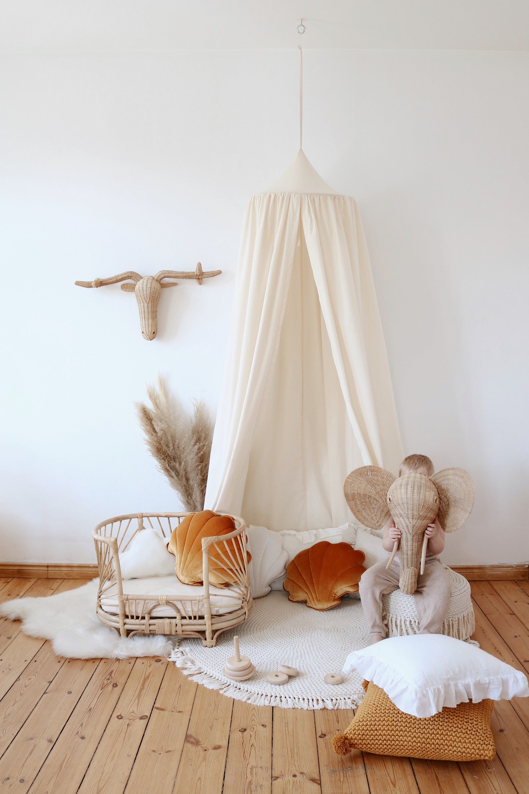 Moi Mili raw cotton canopy styled in a neutral nursery with a child holding a woven elephant mask