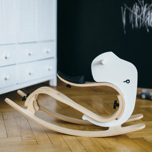 White wooden rocking toy with black seat, modern nursery decor on hardwood floor
