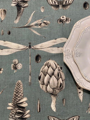 Teal fabric with vintage botanical print featuring dragonflies, pinecones, and moths, styled with ornate white plates