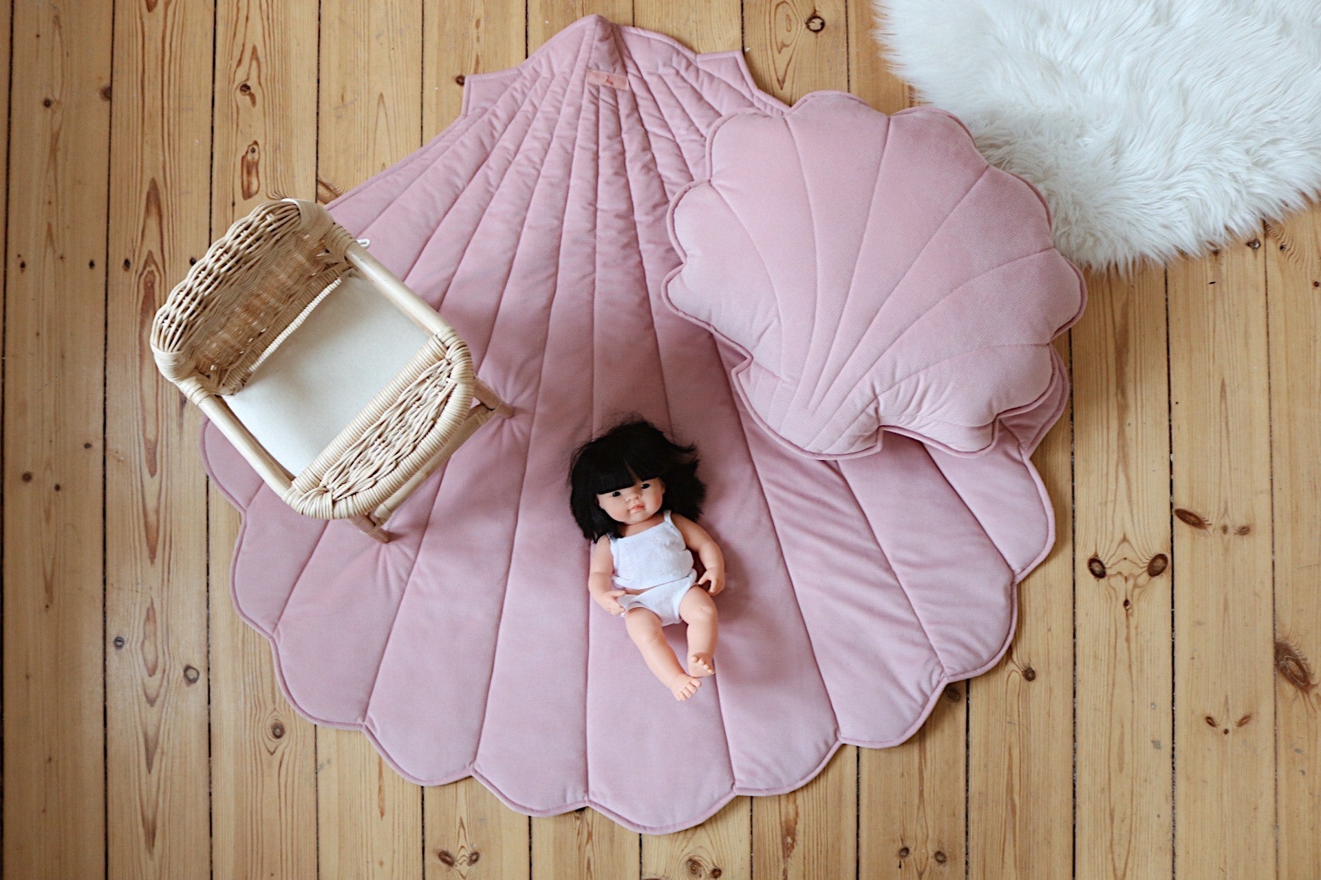 Large powder pink shell playmat styled with a matching shell cushion, doll and miniature rattan chair