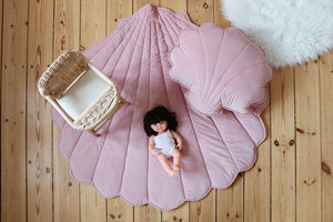 Large powder pink shell playmat styled with a matching shell cushion, doll and miniature rattan chair