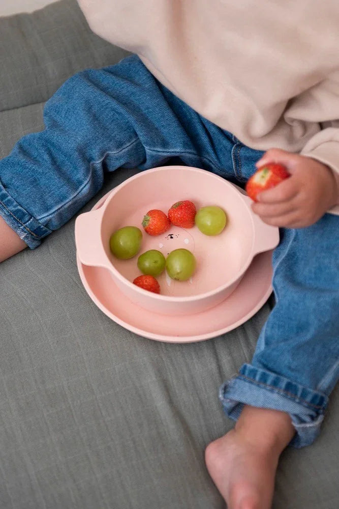 Bol enfant en silicone rose avec design tête de lapin, contenant des raisins et des fraises