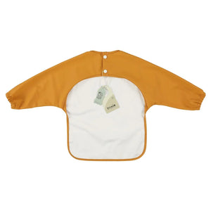 Bavoir bébé imperméable à manches longues jaune moutarde avec boutons-pression au dos, étiquette Trixie visible