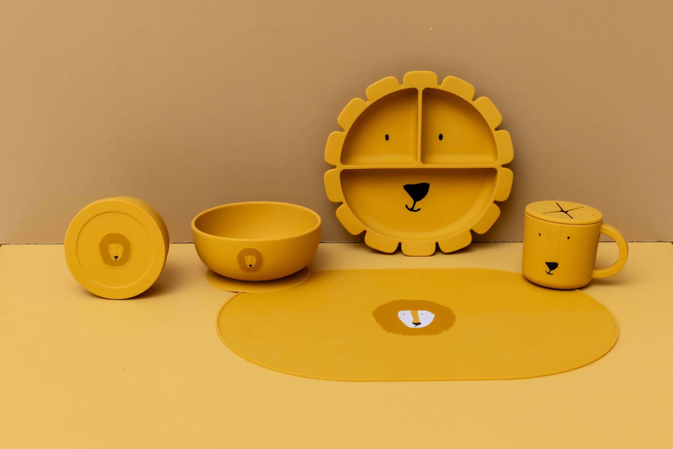 Récipient à goûter en silicone jaune avec couvercle et tête de lion, fait partie d'un set de vaisselle pour enfant