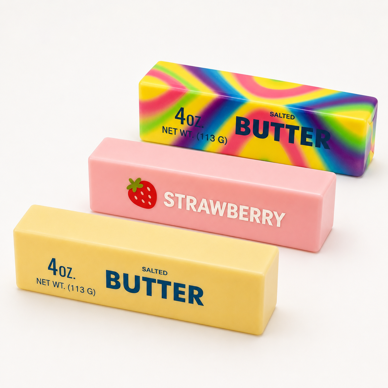 Three rectangular butter-shaped squishy arranged diagonally on a white background: a yellow one labeled 'BUTTER' with salted text, a pink one labeled 'STRAWBERRY' with a strawberry icon, and a rainbow-colored one labeled 'BUTTER'.
