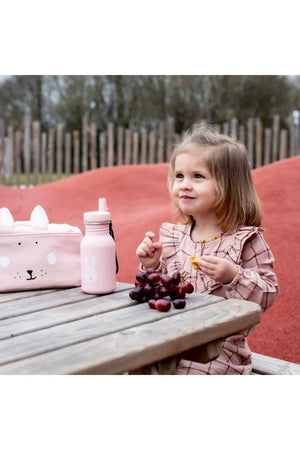 Gourde en inox rose pour enfant avec illustration de lapin et sac à déjeuner assorti sur une table de pique-nique