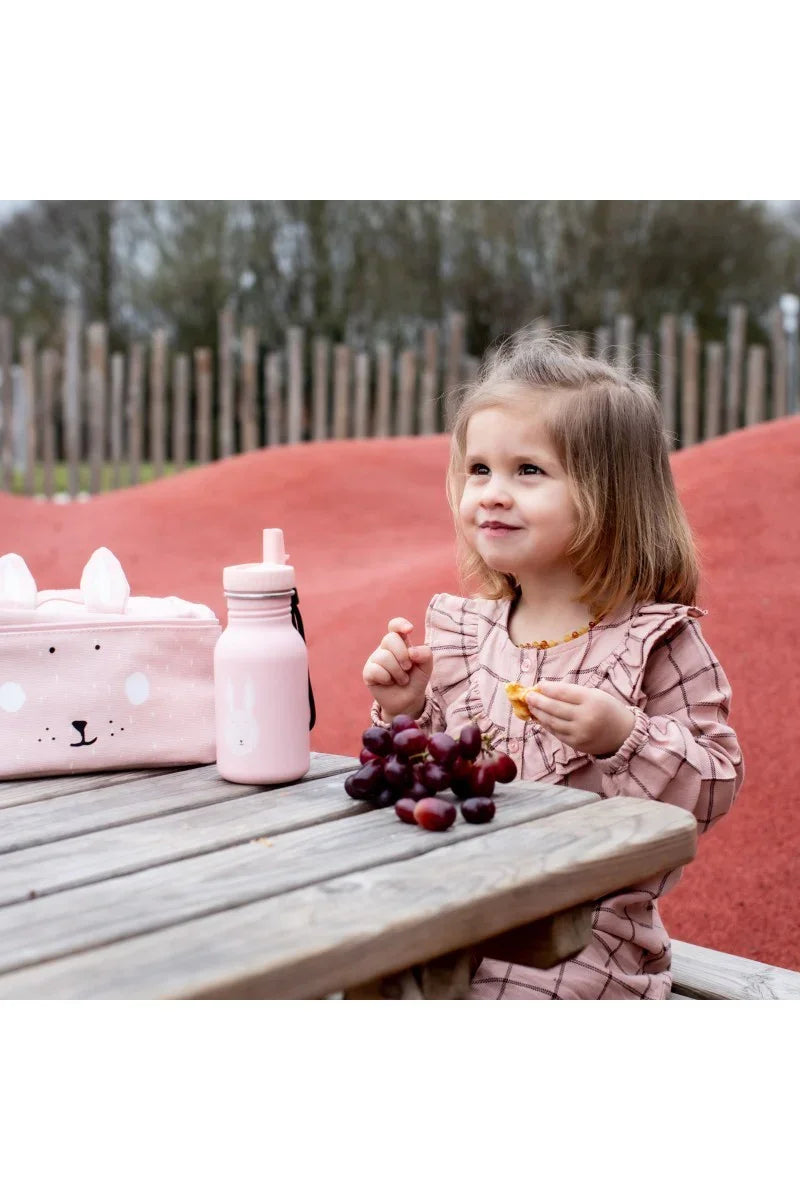 Pink stainless steel kids bottle with bunny illustration and matching lunch bag on picnic table