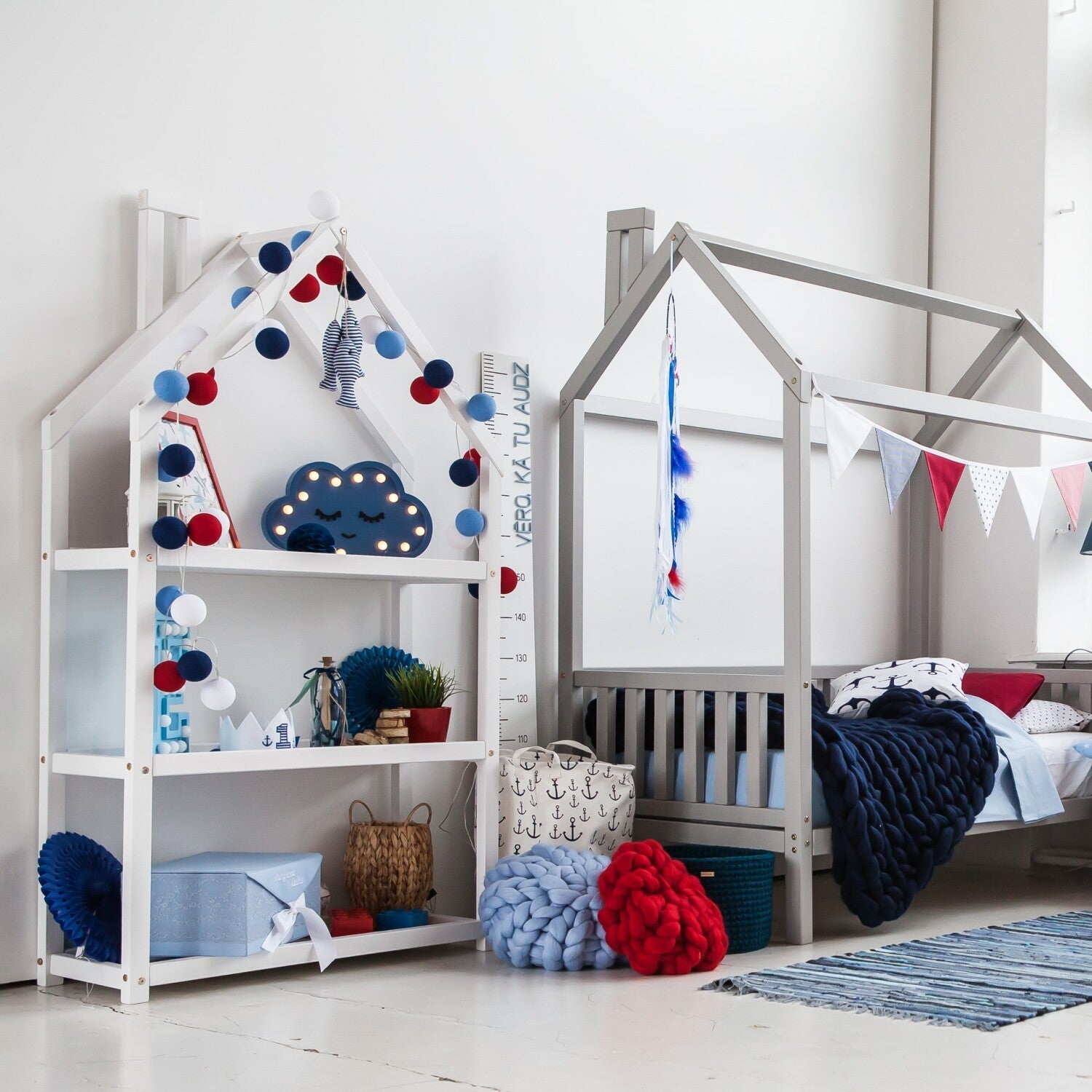 White house-shaped shelf beside matching house bed in a blue, white and red children’s bedroom