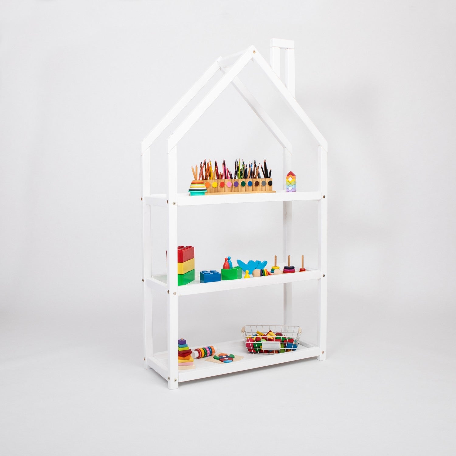 White house-shaped children’s shelf with coloured pencils, building blocks and educational toys