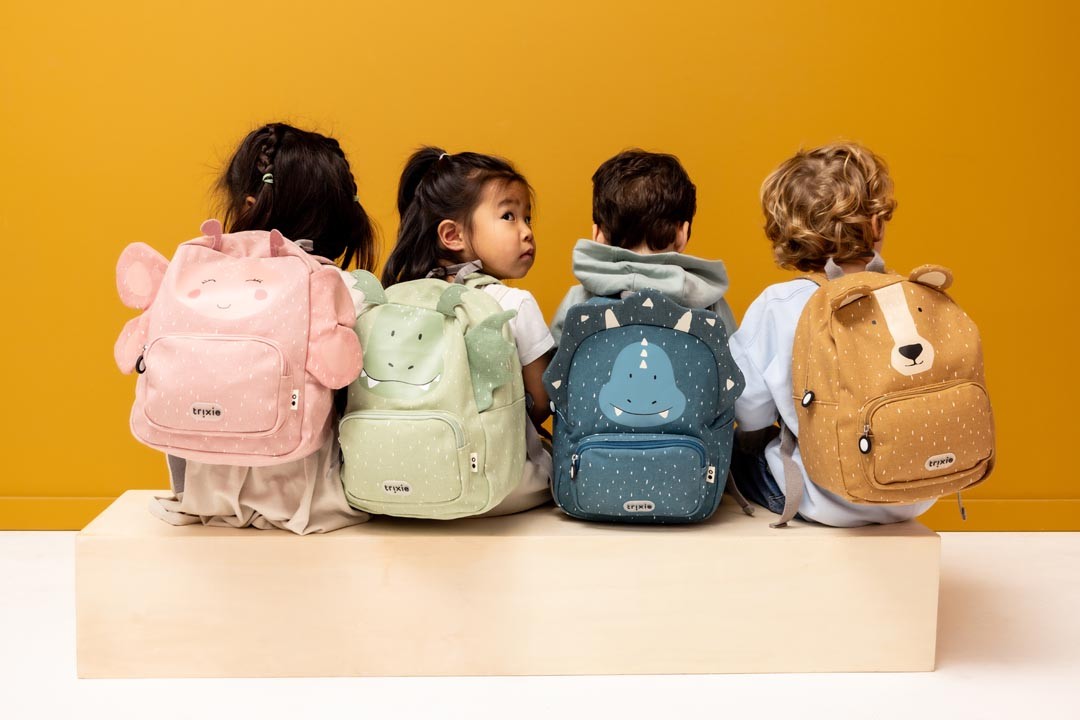 Back view of four children wearing Trixie animal backpacks including the green Mr. Dragon design