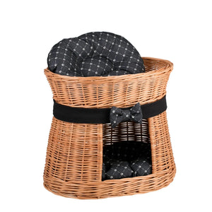 Cuccia per gatti a due piani in vimini, con cuscini neri fantasia e fiocco decorativo; un complemento d'arredo naturale ed elegante.