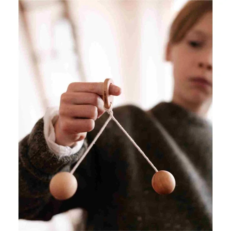 Child holding Wooden Story Bon Bon Ball by the wooden handle with two swinging balls