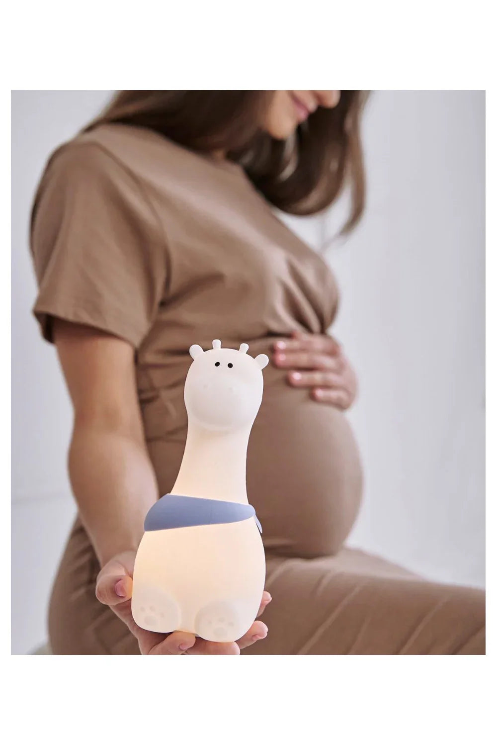 Veilleuse girafe en silicone pour chambre d'enfant, tenue par une femme en robe beige