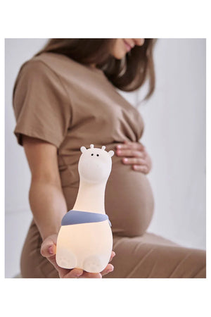 Veilleuse girafe en silicone pour chambre d'enfant, tenue par une femme en robe beige